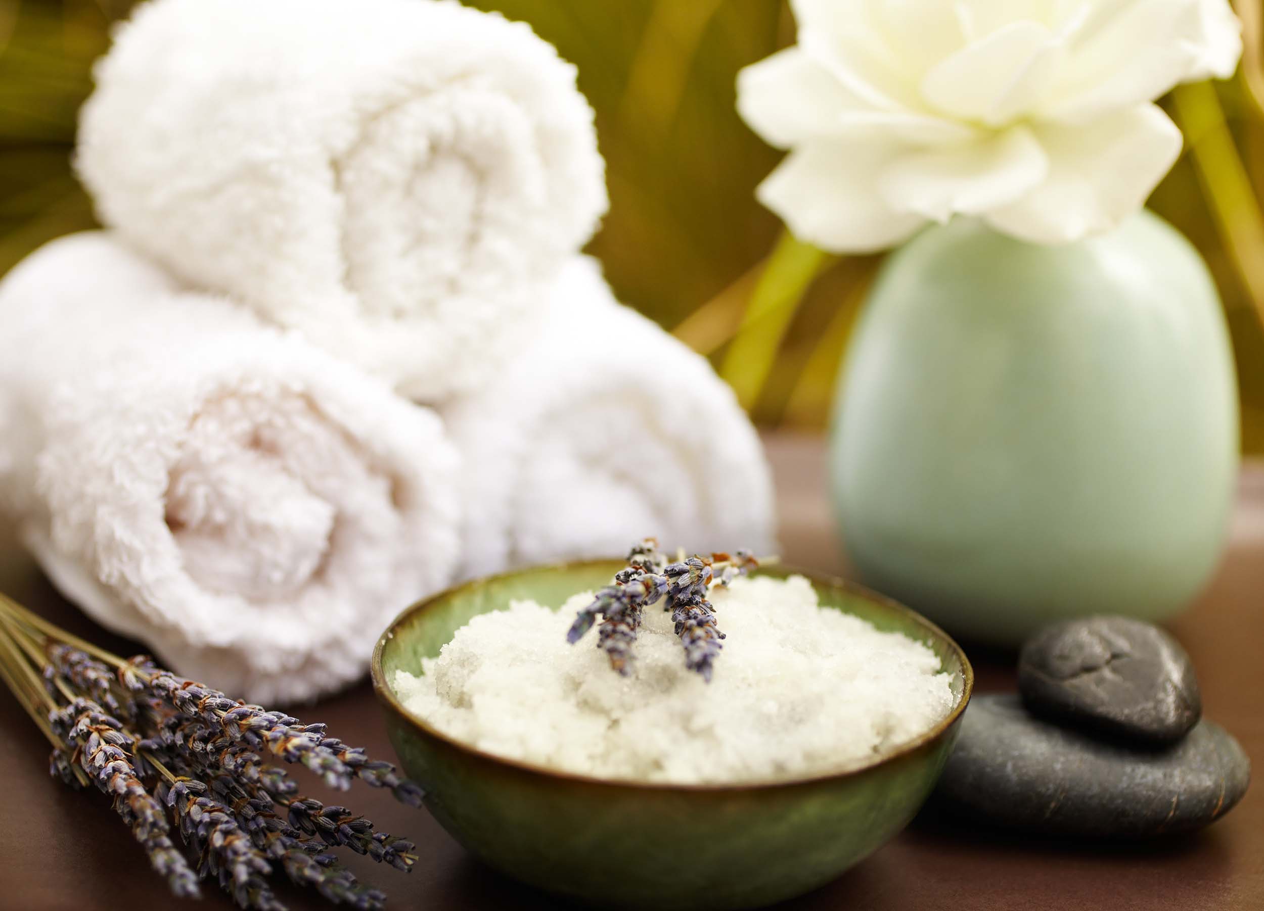 Exfoliation salt scrub at spa with lavender, towels and pebbles