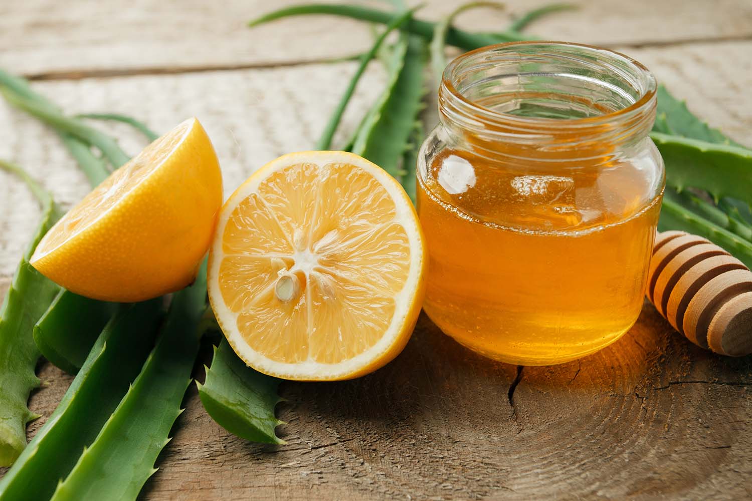 Healthy ingredients for strengthening immunity on wooden background - honey in jar, lemon and aloe vera leaves