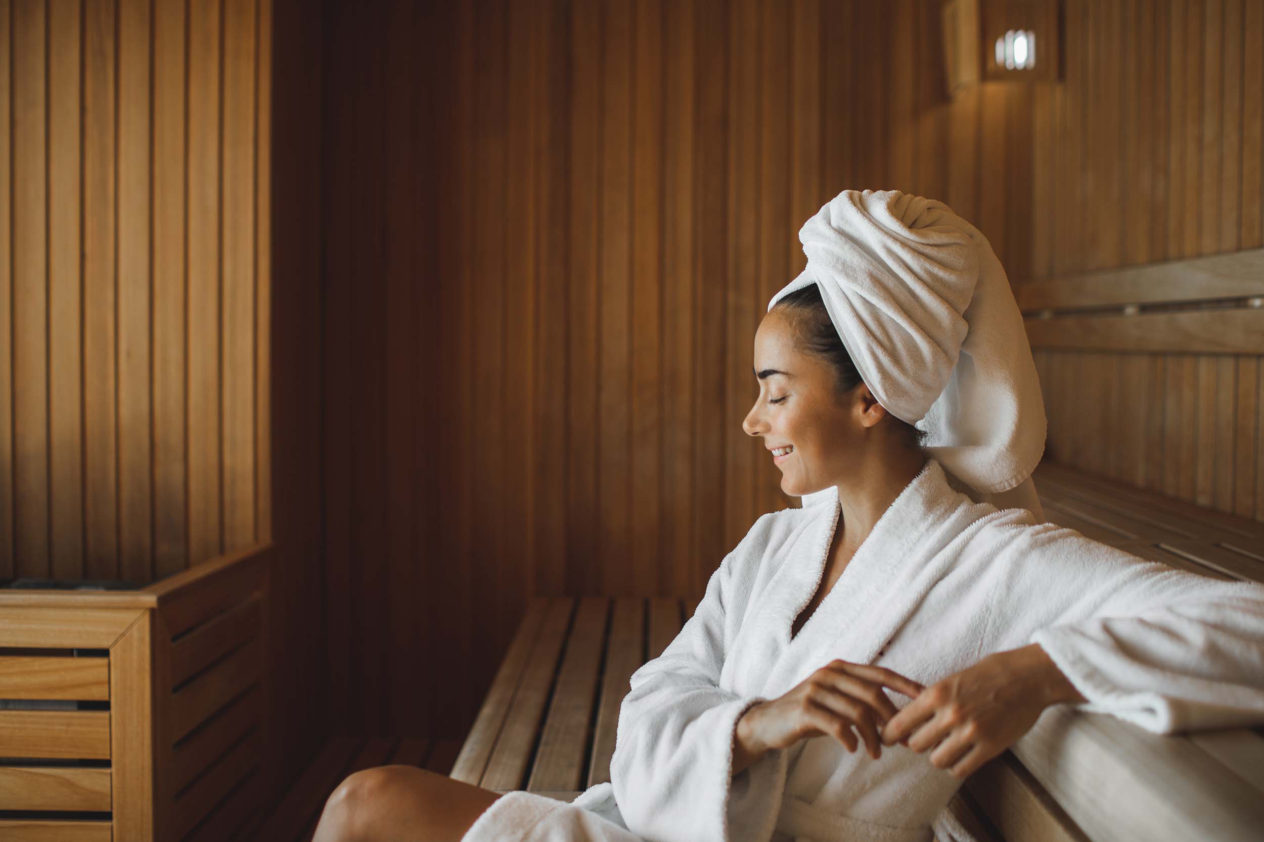 Portrait of young attractive woman smiling and relaxing in sauna at spa.