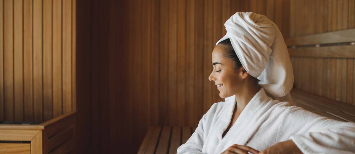 Portrait of young attractive woman smiling and relaxing in sauna at spa.
